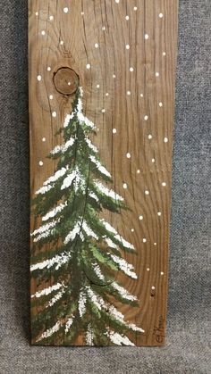 a painting on wood with white snow and a pine tree painted on it's side