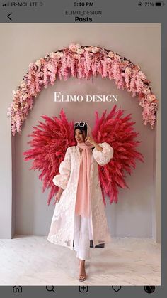 a woman standing in front of a pink floral arch with the words ellimo design on it