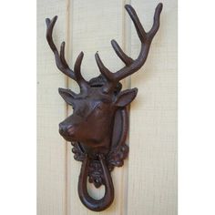 a metal deer head mounted to the side of a wooden door with an iron hook