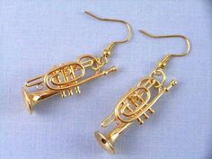 two brass colored musical instruments are shown on a blue surface with gold earwires