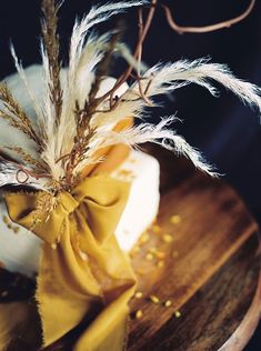 there is a cake decorated with feathers on the top and yellow ribbon tied around it