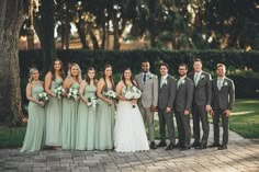 a group of people standing next to each other in front of a tree and bushes