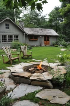 a fire pit in the middle of a yard with chairs around it and a house behind it