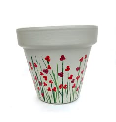 a white flower pot with red flowers painted on it