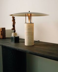 a lamp sitting on top of a wooden table next to a vase and figurine