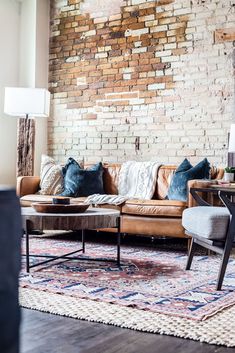 a living room filled with furniture and a brick wall behind the couch is a coffee table