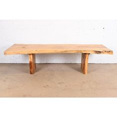 a wooden bench sitting on top of a cement floor next to a white brick wall