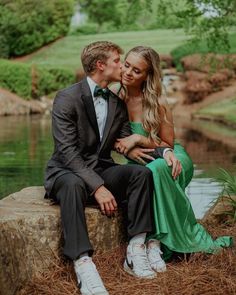 a man and woman sitting next to each other on a rock