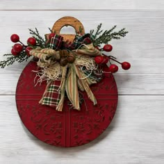 a christmas ornament hanging on a white wooden wall with holly and red berries