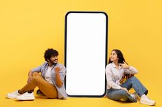 two people sitting next to each other in front of an empty sign on a yellow background