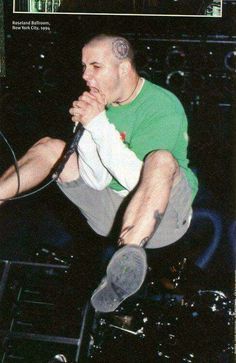 a man in green shirt and grey shorts on stage with his hands over his mouth