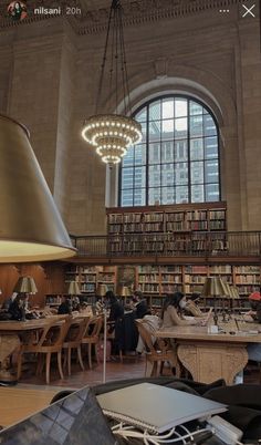 a large library filled with lots of books and people sitting at tables next to each other