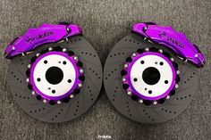 two purple brake discs on top of each other in front of a carpeted floor