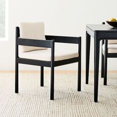 two chairs sitting on top of a rug next to a table with fruit on it