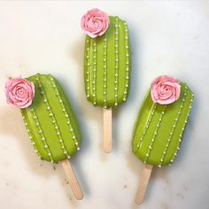 three green and pink popsicles with flowers on them sitting next to eachother