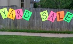 yard sale sign on the grass in front of a fence