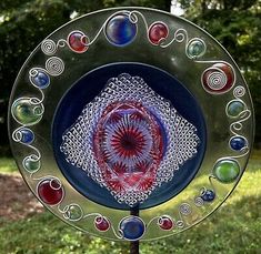 a glass plate sitting on top of a metal stand in the grass next to trees