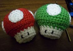 two crocheted mushrooms sitting next to each other on top of a wooden table