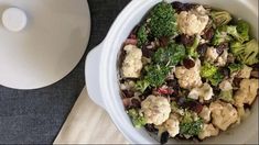 a bowl filled with broccoli and raisins next to a serving dish