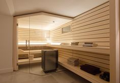 a sauna room with glass walls and wood paneling on the wall, along with towels