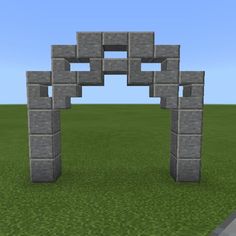 an arch made out of blocks in the middle of a grassy area with blue sky