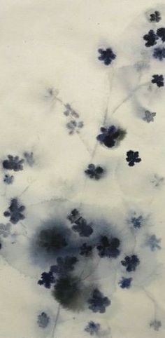 blue flowers are floating in the water on a white surface with black spots and bubbles