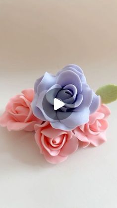 a pink and blue flower with green leaves on it's head is shown in front of a white background