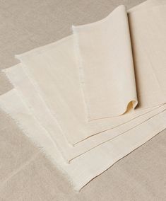 four pieces of white linen folded on top of each other in different sizes and colors