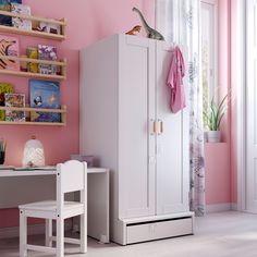 a child's bedroom with pink walls and white furniture, including a toy dinosaur on top of the cabinet