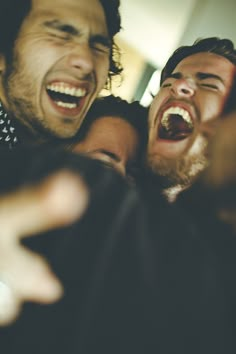 two men are laughing and one is holding his arms around the other's neck