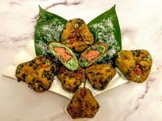 several pieces of food on a white plate with green leaves and powder sprinkles