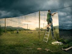 a man climbing up the side of a metal ladder on top of a green field