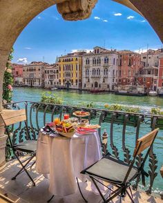 an outdoor table with food on it overlooking the water and buildings in venice, italy