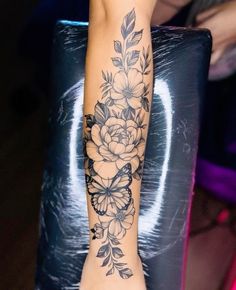 a woman's arm with flowers and leaves on it