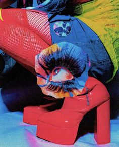 a woman laying on top of a red chair next to a colorful pillow and bag