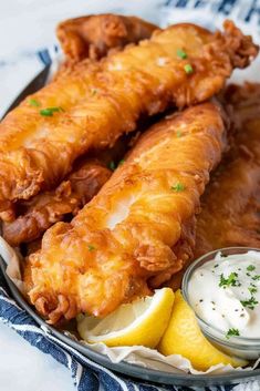 a plate with fried fish, lemon wedges and sour cream