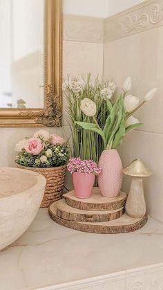 some flowers are sitting in vases on the counter next to a sink and mirror