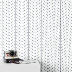 a camera sitting on top of a white table next to a wall with an arrow pattern