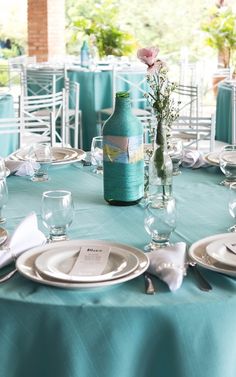 the table is set with plates, silverware and vases for flowers on it