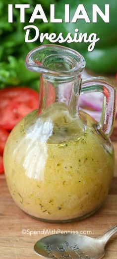 a glass bottle filled with dressing sitting on top of a wooden cutting board next to vegetables