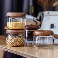 three glass jars filled with food sitting on top of a wooden table next to a laptop computer