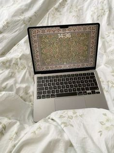 an open laptop computer sitting on top of a bed