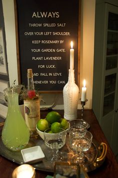 a table topped with glasses and bottles filled with limes next to a chalkboard