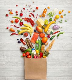 a paper bag filled with assorted fruits and vegetables