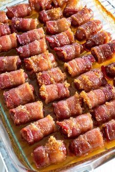 bacon wrapped in small pieces on a baking sheet with sauce and seasoning sprinkles