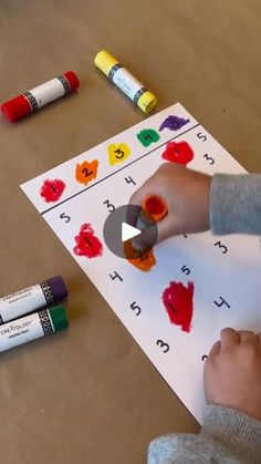 a young boy is painting with crayons on paper