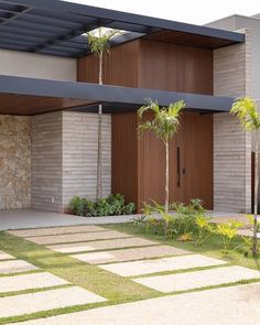 a modern house with stone walkway and palm trees in the front yard on a sunny day