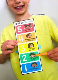 a young boy is holding up a sign with numbers and pictures on it that say feelings