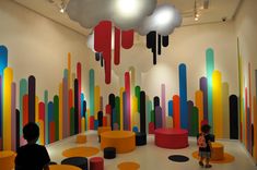 two children are sitting in front of an art exhibit with colorful paint on the walls