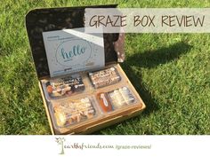 an open suitcase filled with treats sitting on top of a green grass covered field next to a sign that says graze box review